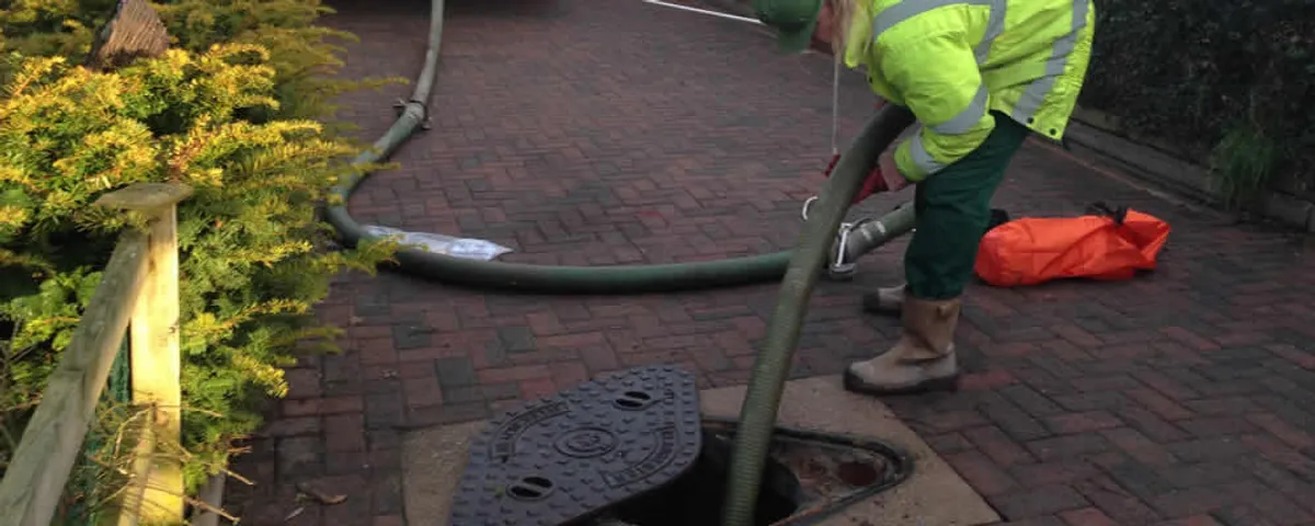 Septic tank cleaning technician servicing a septic tank with a vacuum hose in Ogden, UT